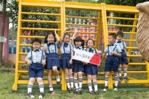 Cheerful children in school uniforms playing outside by a climbing frame, enjoying a sunny day.