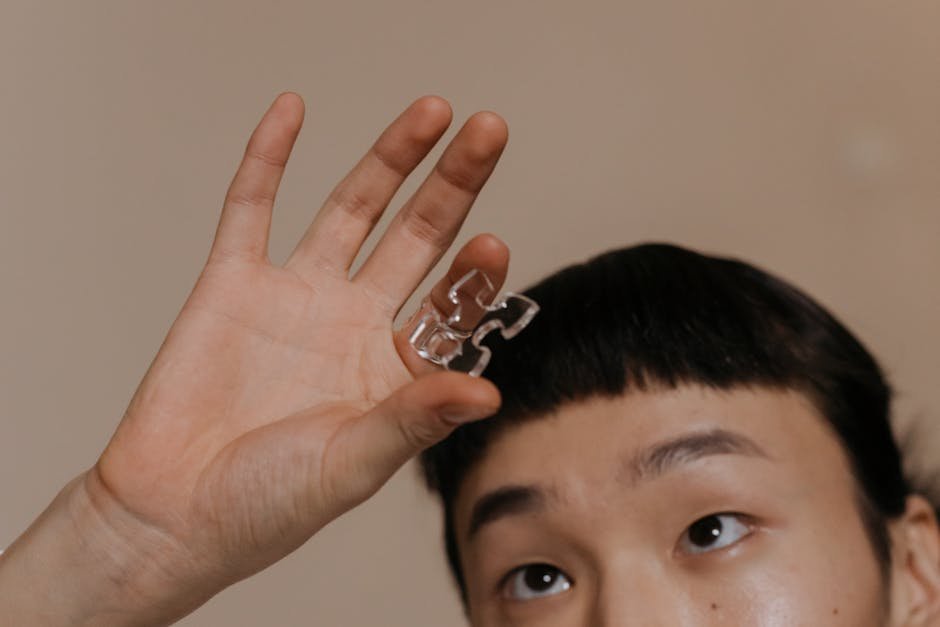 Person holding a transparent puzzle piece, focusing on the hand and expression.