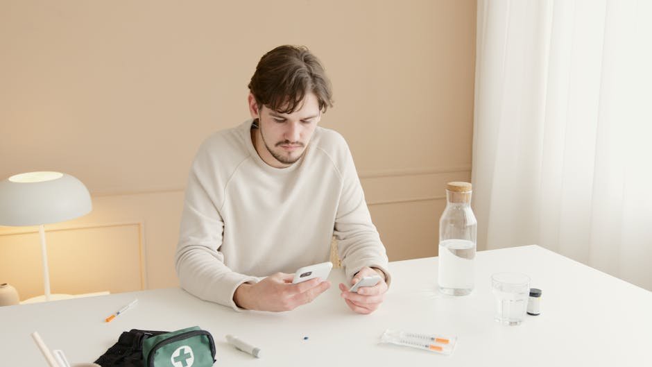 Young man checking glucose levels with a smartphone indoors at a home setting.
