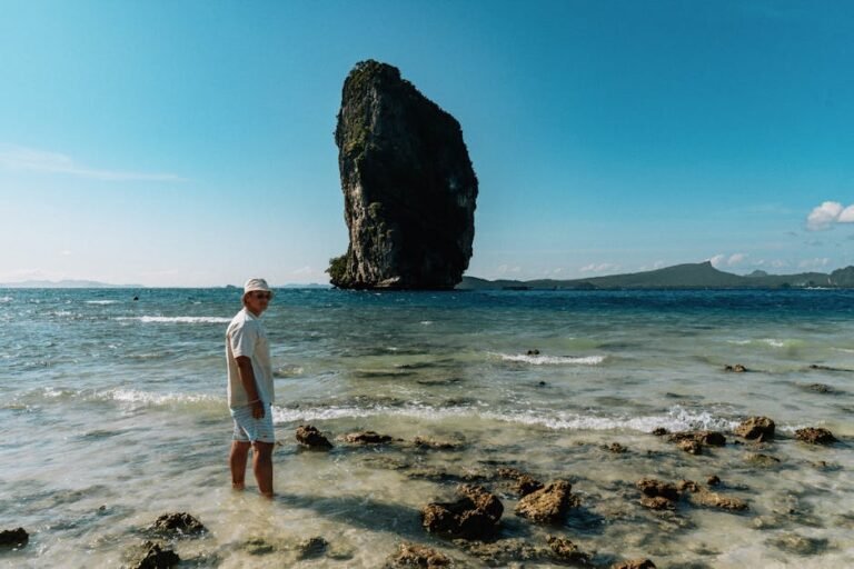 Person on a tropical beach with a massive limestone rock in the background, Krabi, Thailand.