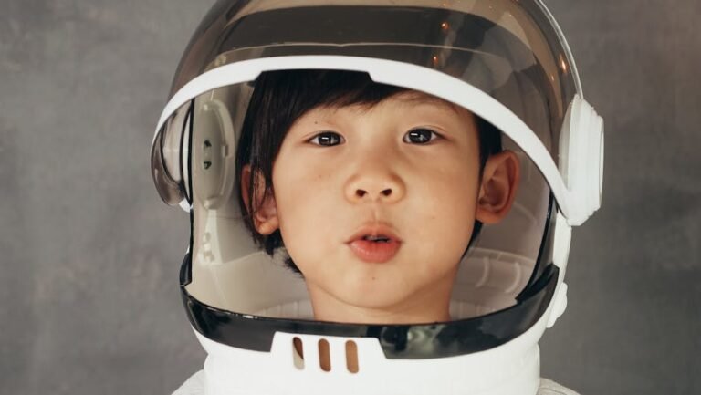 A young child wearing an astronaut helmet with an adorable expression.