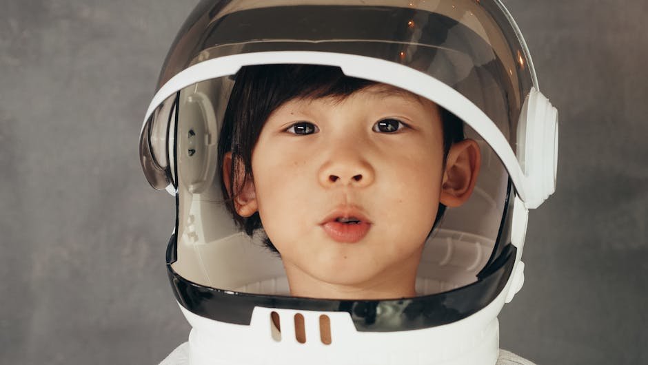 A young child wearing an astronaut helmet with an adorable expression.