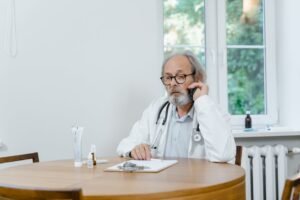 A senior doctor making a telemedicine call in an office setting, discussing medical cases.