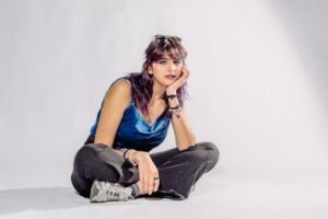 Artistic portrait of a young woman seated in a studio with expressive pose.