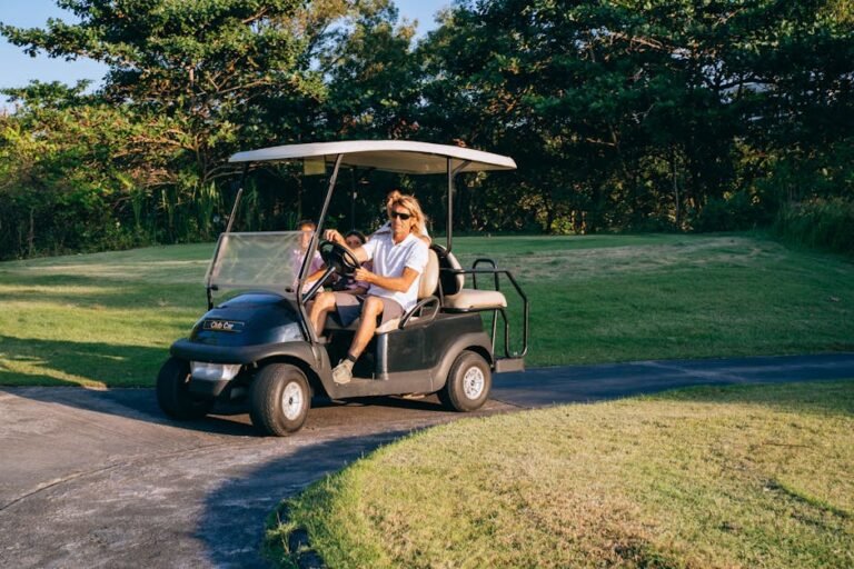 A family rides a golf cart on a sunny day in a lush golf course setting.