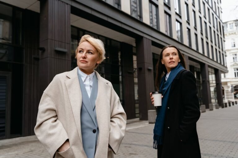 Two women in stylish professional attire walking in a modern urban environment.