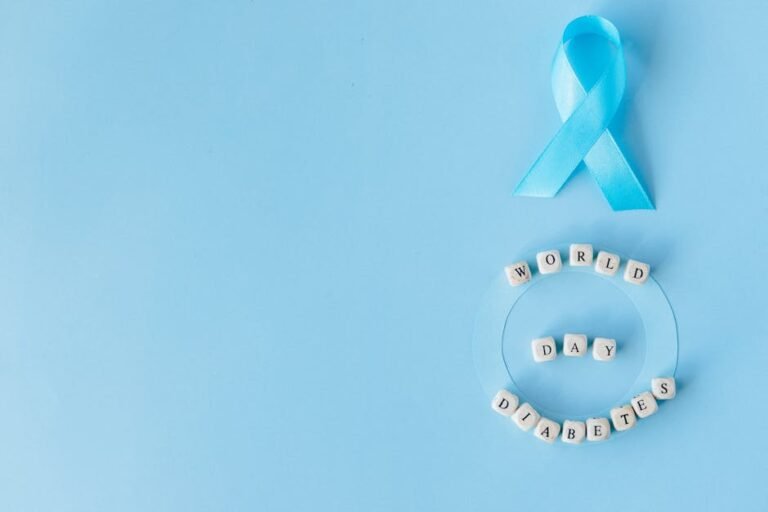 Flat lay of blue ribbon and letter blocks spelling 'World Diabetes Day' on a blue background.