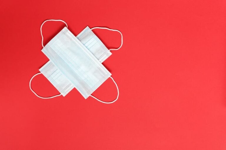 Two surgical masks placed on a vibrant red background symbolizing health and safety.