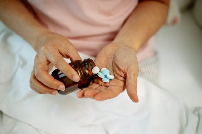 An anonymous woman in bed pouring blue and white pills from a brown bottle into her hand.